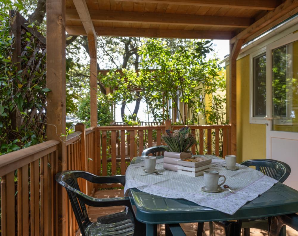 Veranda accogliente con tavolo apparecchiato, immersa nel verde e nella tranquillità.